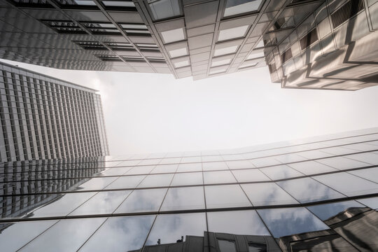 The image features towering modern skyscrapers with shining reflective glass facades, framing a patch of sky, epitomizing urban advanced architecture and progress.