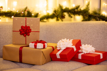 Set of beautifully wrapped gift boxes on sofa with Christmas decor on background, winter holidays...