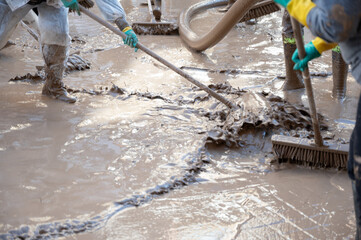 People cleaning and sweeping a muddy area after a severe flood in Valencia. Effects of the DANA