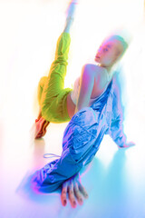 Contemporary art collage. Woman stretching dynamically on floor, wearing vibrant athletic clothing, surrounded by glowing neon light effects. Concept of fashion, style, lifestyle. Motion blur effect.