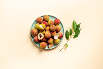 Juicy lychee fruit with cut in half and green leaves, top view. Fresh ripe tropical fruit