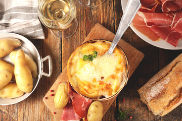 Mont d'or cheese. Traditional french meal with melting cheese fondue, potato, ham and glass of wine.