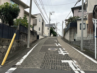 uphill street in in Nagoya, Japan - houses, utility poles and wires, brick walls and foundations,...