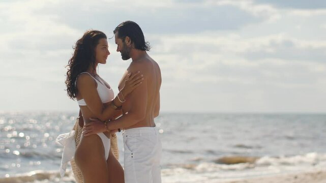 A rich, tanned newlywed couple shares a romantic moment on a sunny beach, enjoying their honeymoon by the ocean. Perfect for themes of love, travel, and luxurious lifestyle. 