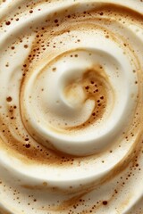 Thick, creamy foam swirls elegantly above a freshly brewed latte, featuring rich espresso hues blended with velvety milk in a cafe ambiance