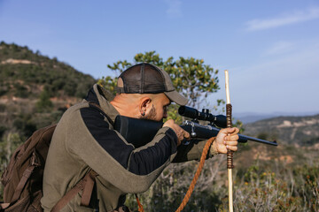 Naklejka premium Hunter aiming with rifle in forest during hunt