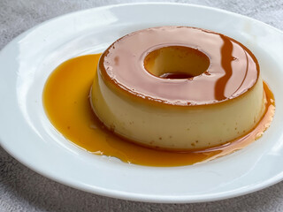 Delicious caramel drizzled milk pudding on a white plate.