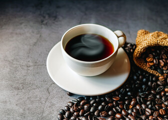 Americano coffee cup and roasted coffee beans falling in a burlap sackon gray background, Black coffee cup aromatic