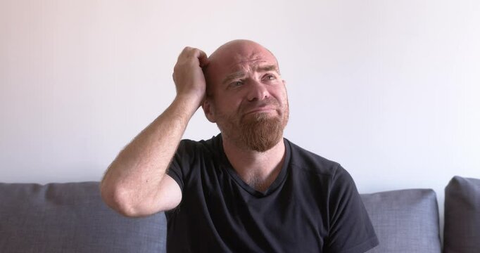 Bald man scratches head in puzzlement