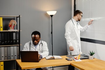 Doctor discussing diagnosis with young colleague in office