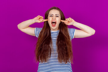 Deaf to the World. Furious Young Woman Covers Ears in Frustration, Shutting Out Noise. Standing against a bright colorful background