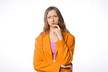 thoughtful and concerned young woman with a serious expression looking at the camera. Concept of introspection and concern. Female posing on a white studio background, wearing an orange blazer