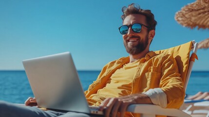 Happy man working on laptop on the beach.