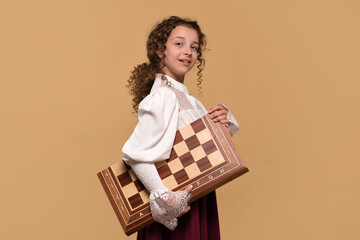 Young girl proudly carrying large wooden chessboard