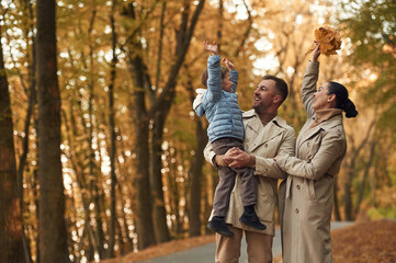 Happy family are together in the autumn forest near the road