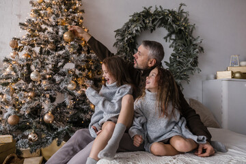 A father and his two daughters create lasting holiday memories while decorating a stunning Christmas tree.
