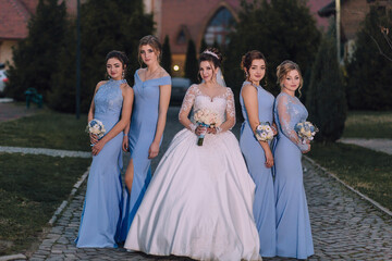 A group of women in blue dresses are posing for a photo. The bride is in the center of the group,...
