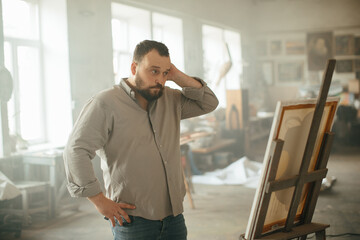 Male artist painting on canvas in a sunlit art studio