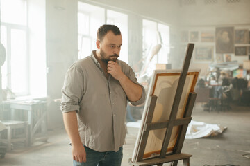 Male artist painting on canvas in a sunlit art studio