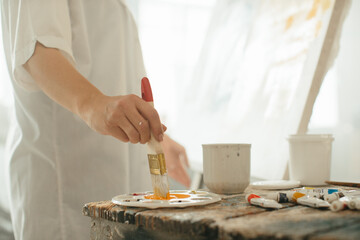 Close-up of a female painter working with brushes and paints