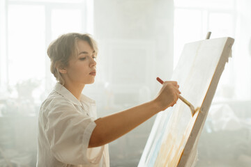 Woman artist adding bold strokes of paint to her canvas