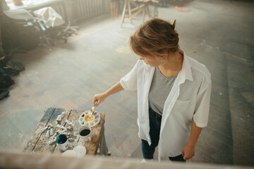 Top view, young artist working with acrylic on canvas in art studio.
