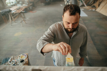 Top view of a male artist working on a canvas in his workshop.