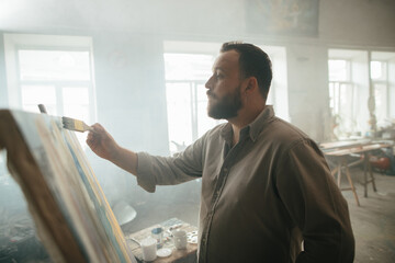 Focused male painter working on a new artwork