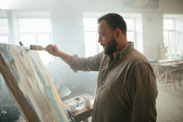 Focused male painter working on a new artwork