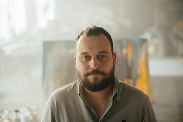 Portrait of a male painter in a creative workspace with abstract art in the background