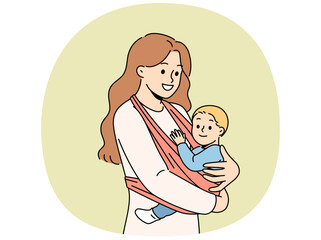 Mother holds baby in carrier sling and smiles, taking care of son and using comfortable babywearing. Caring happy woman with newborn, recommends purchasing sling for young mothers.