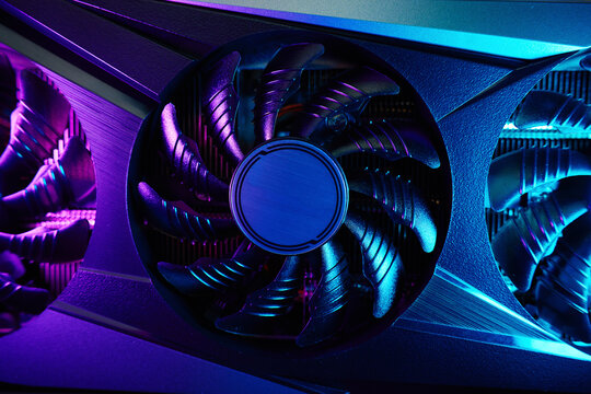 Close-up of high-performance graphics card with cooling fans illuminated by neon lighting. Modern video card for gaming and advanced computing
