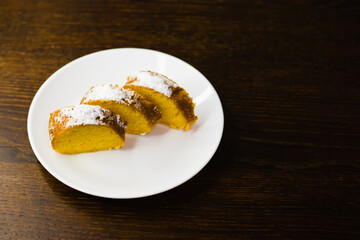 Delicious pumpkin cupcake cut into pieces on a white plate on a dark wooden table