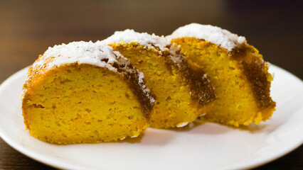 Delicious pumpkin cupcake cut into pieces on a white plate on a dark wooden table