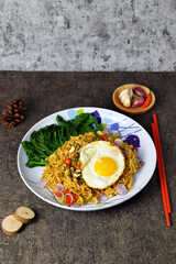 Fried noodles with sunny side up egg and mixed vegetables on a plate