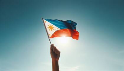 A proud hand holding the Filipino flag against a clear blue sky, symbolizing patriotism and national pride