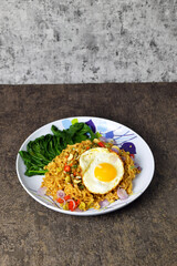 Fried noodles with sunny side up egg and mixed vegetables on a plate