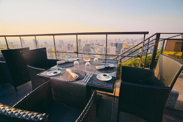 Fototapeta premium Table setting on roof top restaurant with megapolis view, Bangkok Thailand.