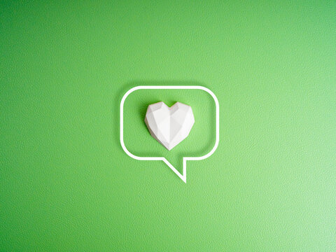 Environment care concept. White geometric heart stone in speech bubble frame isolated on green background. Generic social media likes notifications. Love, donate and charity concept, minimalist.
