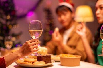 A person is holding a wine glass at a table with food