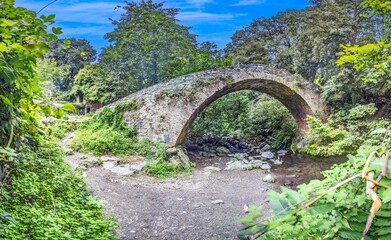 Historic stone bridge Pont du Bucatoghju in Corsica surrounded by lush greenery and natural beauty