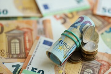 Roll of euro currency money bills and many euro cents on banknotes of european union