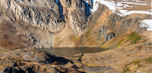 Panorama of an Alpine lake at a high elevation above the treeline on the Beartooth Highway on a bright day