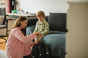 Mother helping her son get ready for school. Good parenting childcare concept.