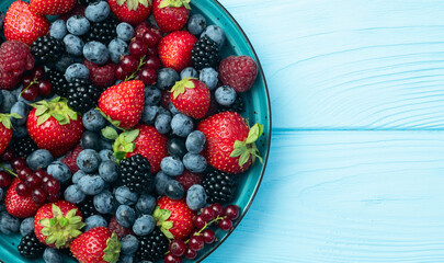 Mix of ripe colorful berries in bowl photography . Blueberry , strawberry , raspberry , blackberry and red currant . Top view