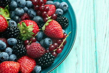 Mix of ripe colorful berries in bowl photography . Blueberry , strawberry , raspberry , blackberry and red currant . Top view