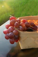 Fototapeta premium Close-up vertical shot of red grapes hanging out of basket in the early morning with blur background