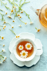 Chamomile flower tea. A tea cup and a tea pot with fresh medicinal flowers, natural organic remedy, shot from the top