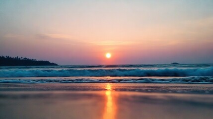 Obraz premium The sun descends on the ocean, casting waves towards the shore as a distant island looms in view