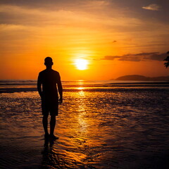 Fototapeta premium silhouette man standing on the beach with sunset view